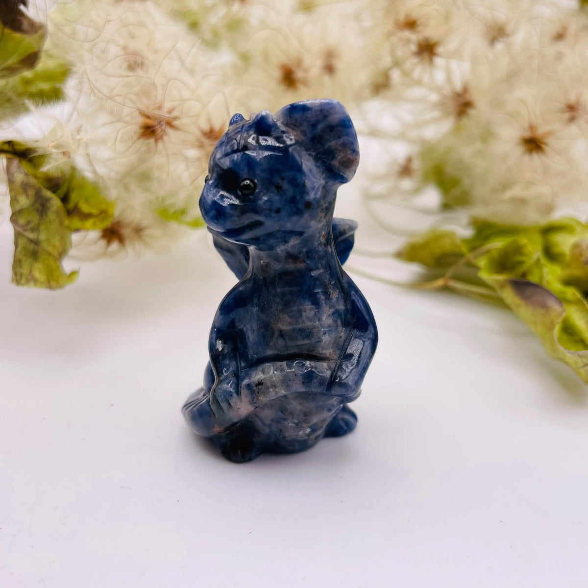 Seitenansicht auf den handverlesenen Sodalith-Drachen von WUNDERSTEIN: blaue Marmorierung mit weißen Einschlüssen auf glänzender Oberfläche