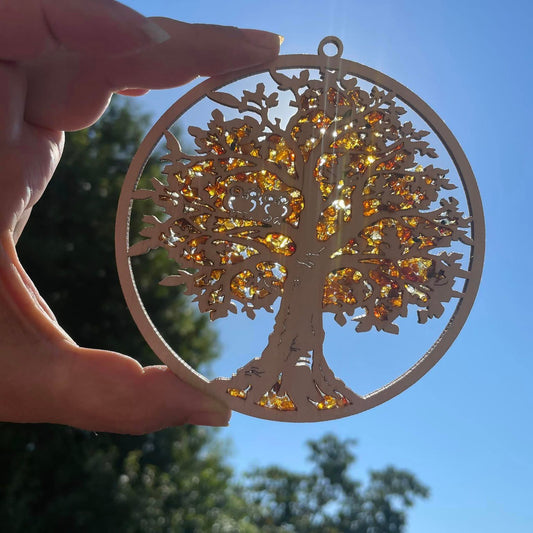 Nahaufnahme: Goldene Bernsteinstücke auf Birkenholz-Eulen – leuchtet warm im Sonnenlicht