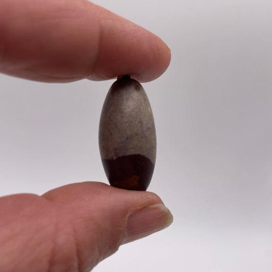 Nahaufnahme: Shiva Lingam Anhänger ca. 3cm mit Silberöse rotbraun gestreift – Narmada-Stein Naturunikat handverlesen von WUNDERSTEIN