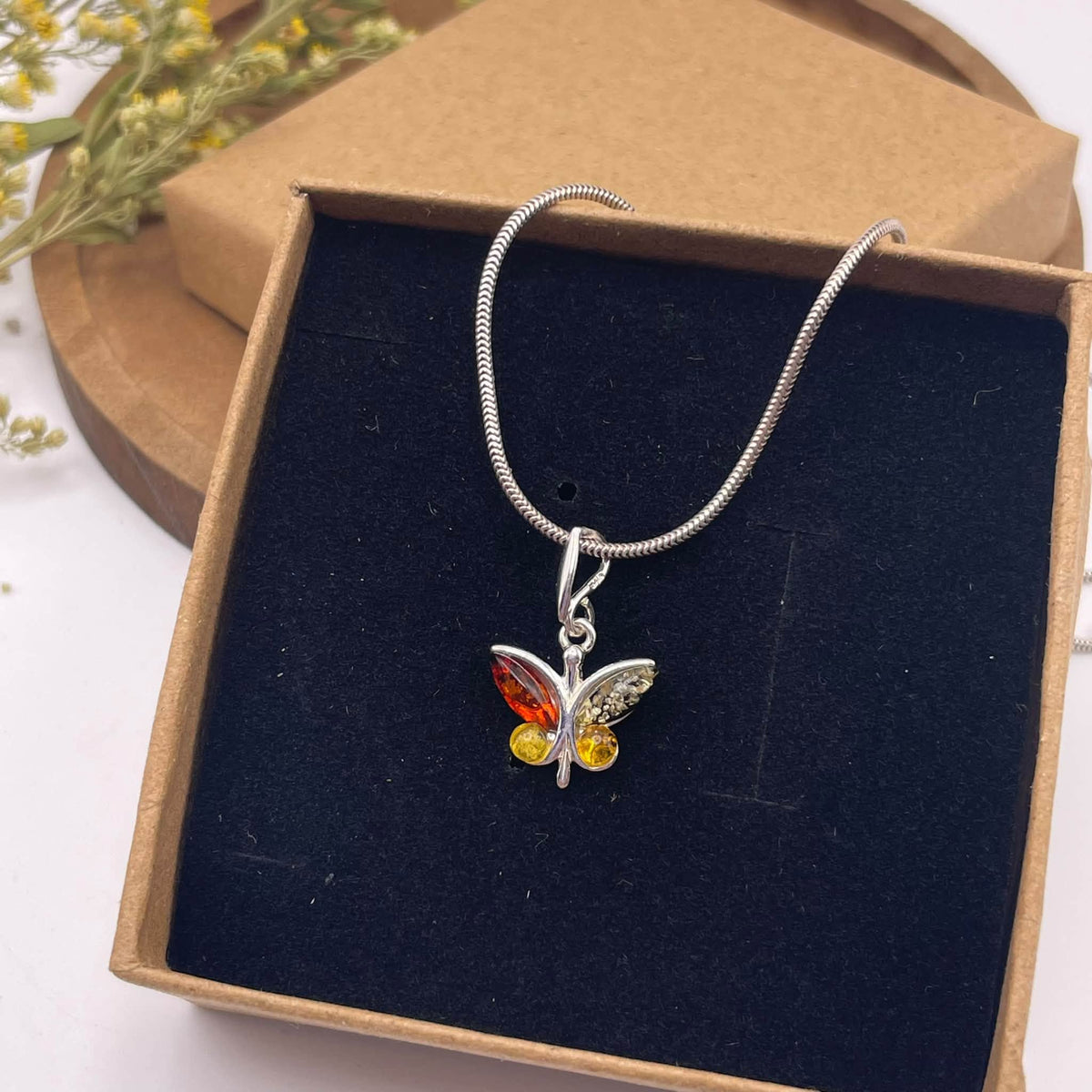 Draufsicht auf Bernstein-Anhänger Schmetterling – handverlesener Amber in Schmetterlingsform mit 925er Silberfassung, Naturunikat von WUNDERSTEIN
