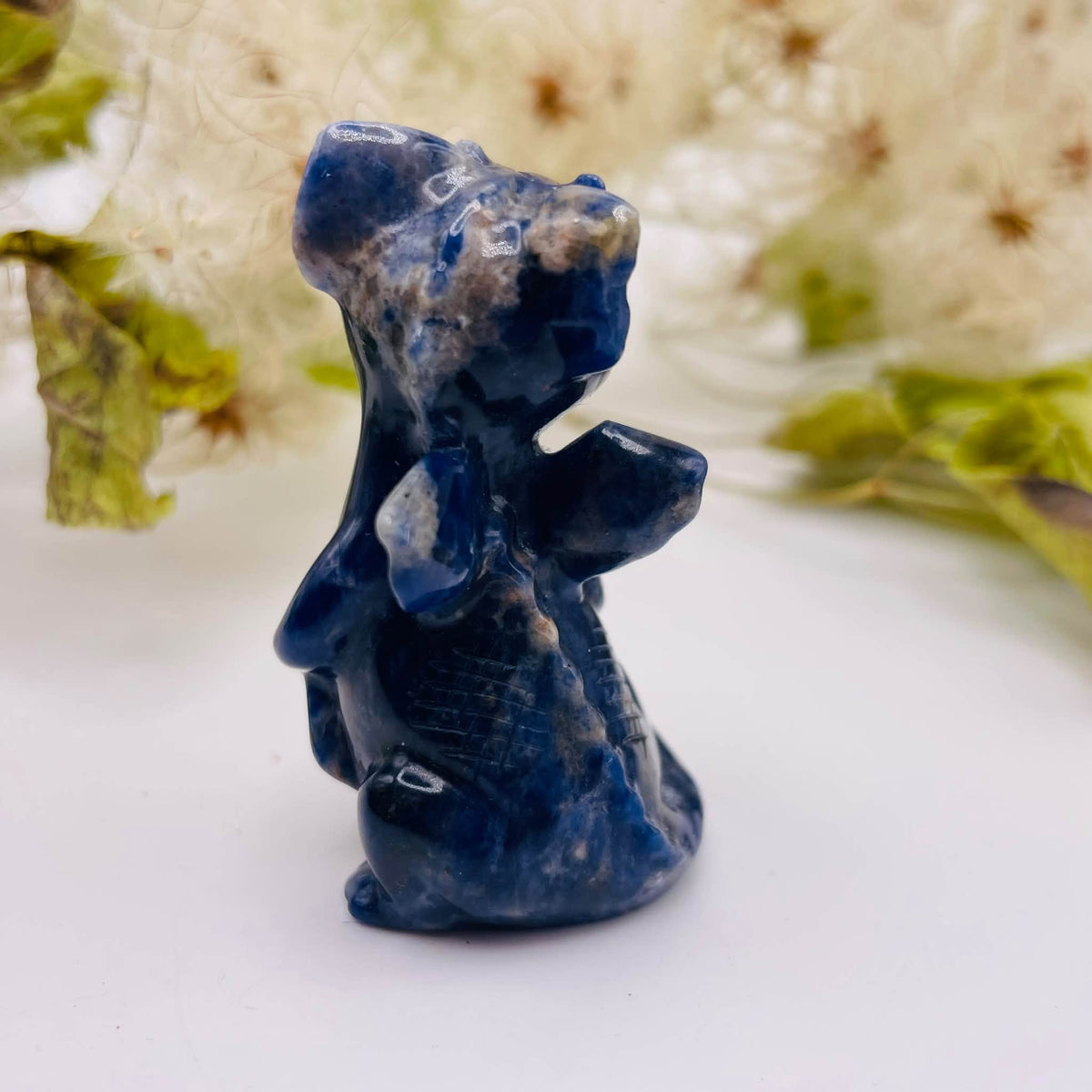 Rückansicht auf den handverlesenen Sodalith-Drachen von WUNDERSTEIN: blaue Marmorierung mit weißen Einschlüssen auf glänzender Oberfläche
