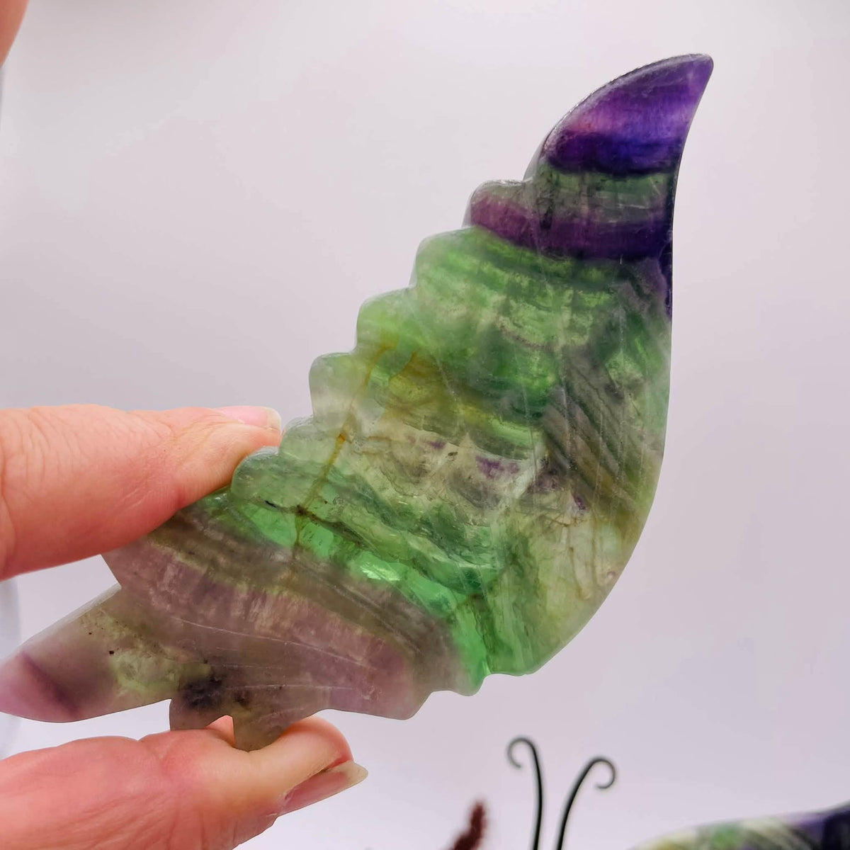 Nahaufnahme der aus Fluorit gearbeiteten Schmetterlingsflügel mit grüner Bänderung, violetten Spitzen und fein ausgearbeiteten Flügeladern
