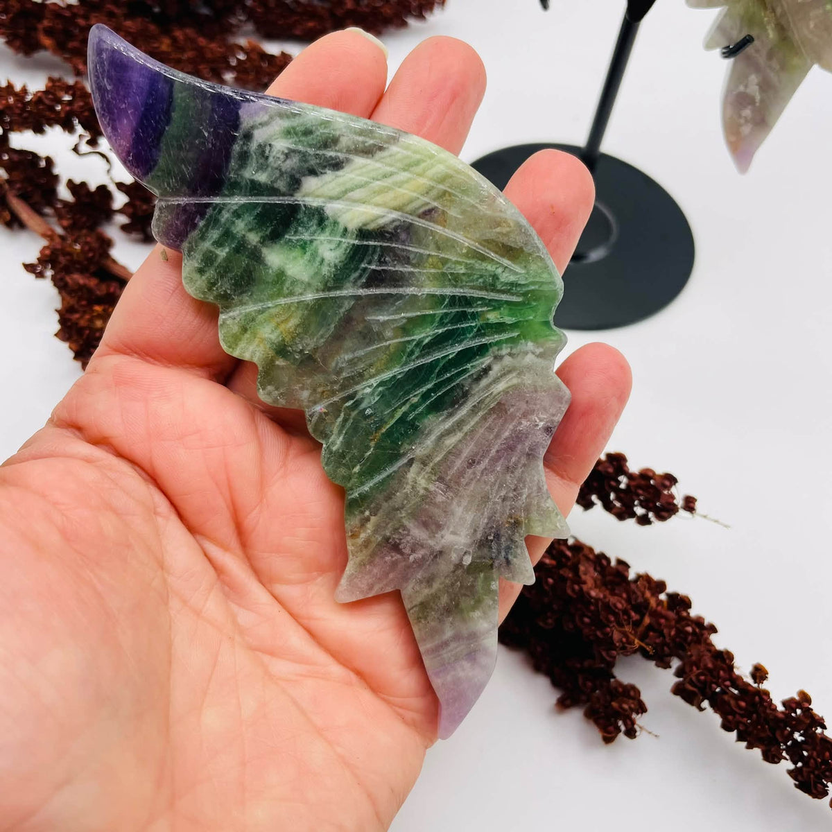 Draufsicht auf den handverlesenen Fluorit-Schmetterling von WUNDERSTEIN: grün-violette Flügel mit natürlicher Maserung auf Metallständer
