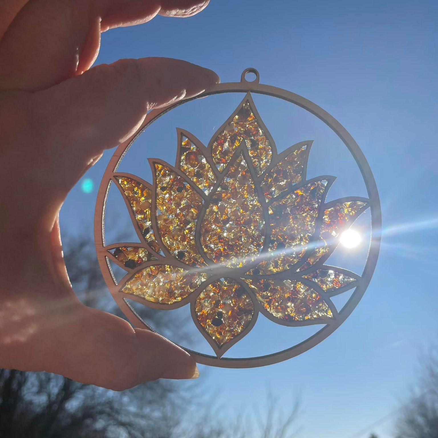 Nahaufnahme: Goldene Bernsteinstücke in Lotusblüten-Form auf Birkenholz – leuchtet warm im Sonnenlicht
