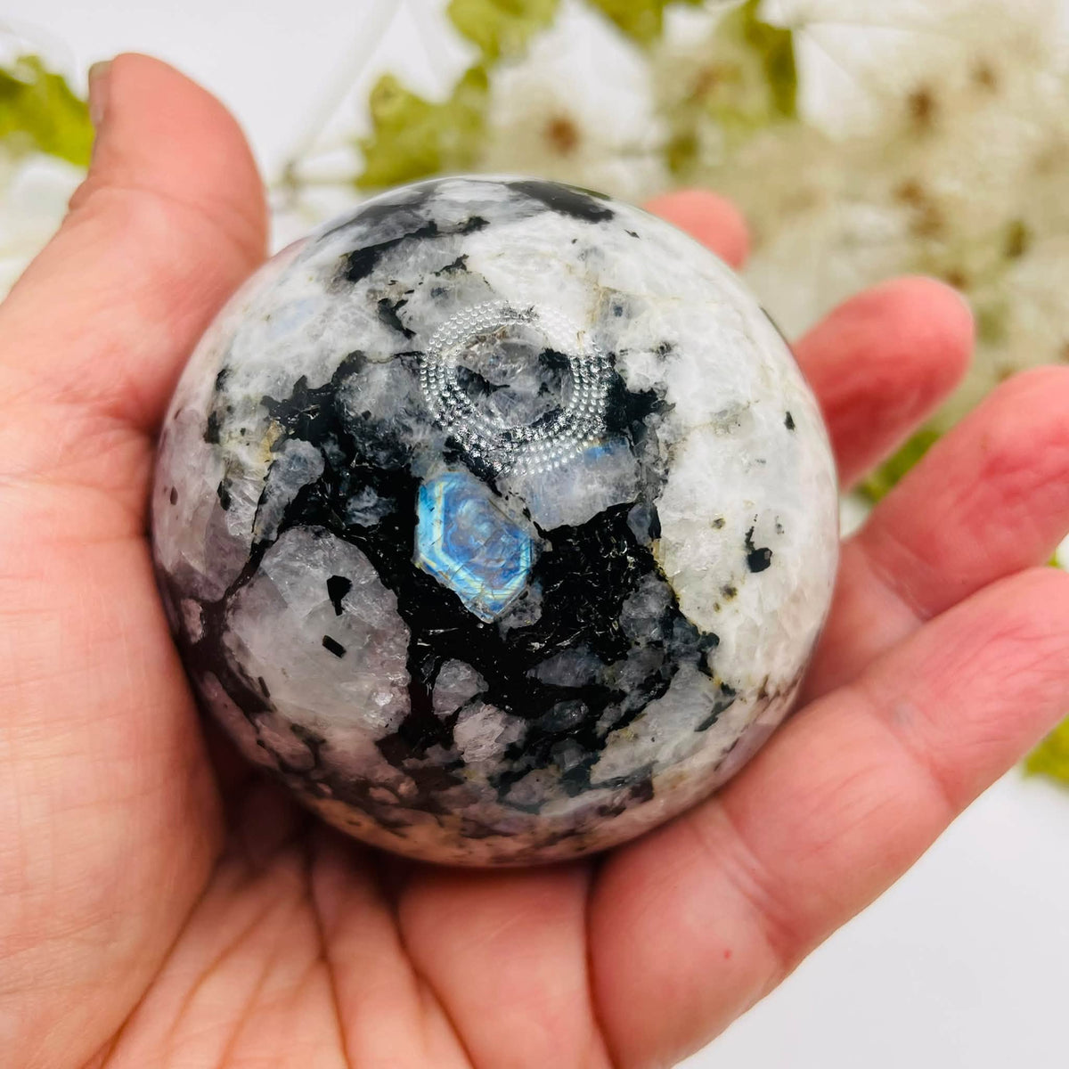 Mondstein-Kugel von oben in einer Hand, mit kontrastreicher weiß-dunkler Zeichnung und blauem Schimmer – handverlesen von WUNDERSTEIN
