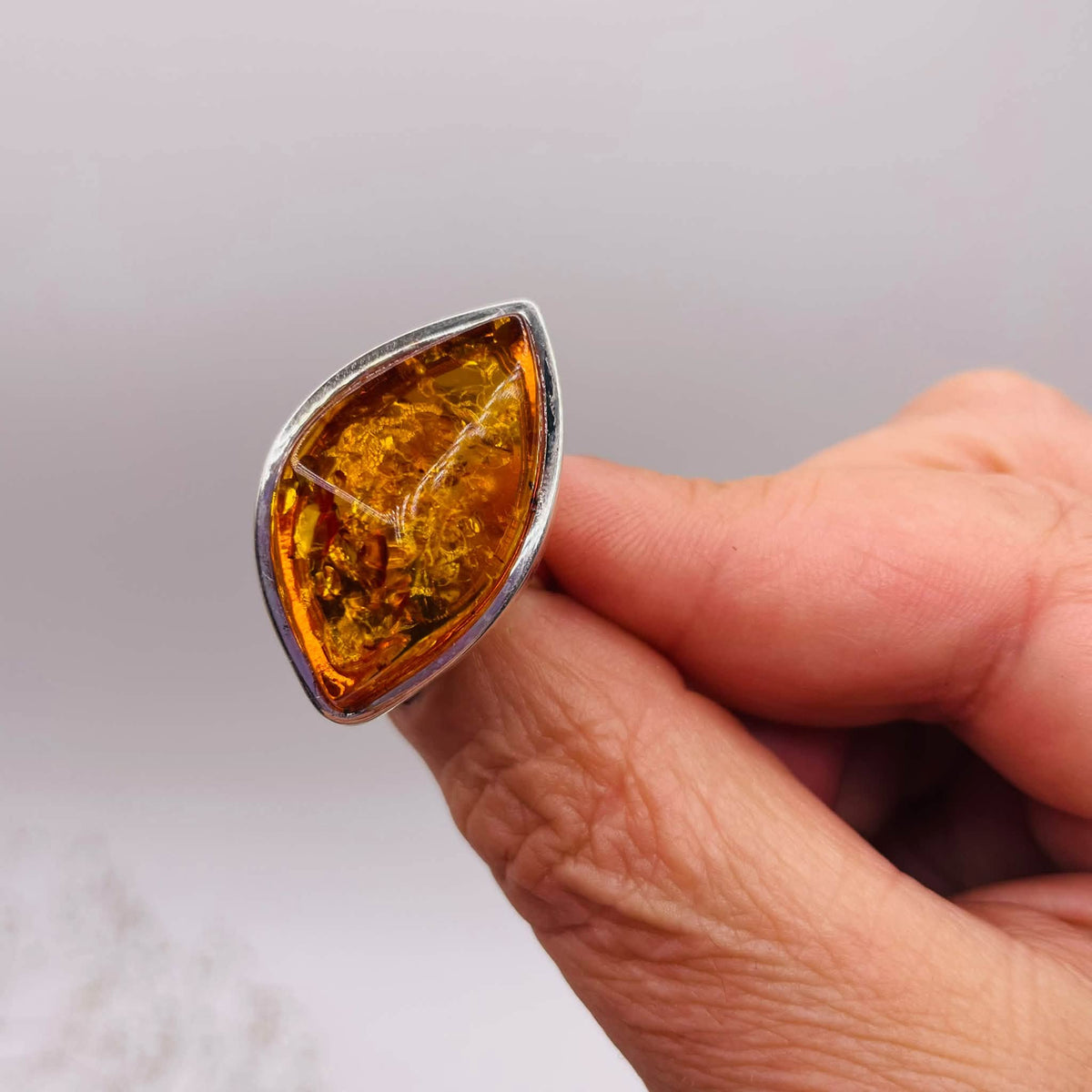 Nahaufnahme des handverlesenen Bernstein-Rings Navette mit warmem Orangeton, natürlicher Struktur und feinen Farbnuancen
