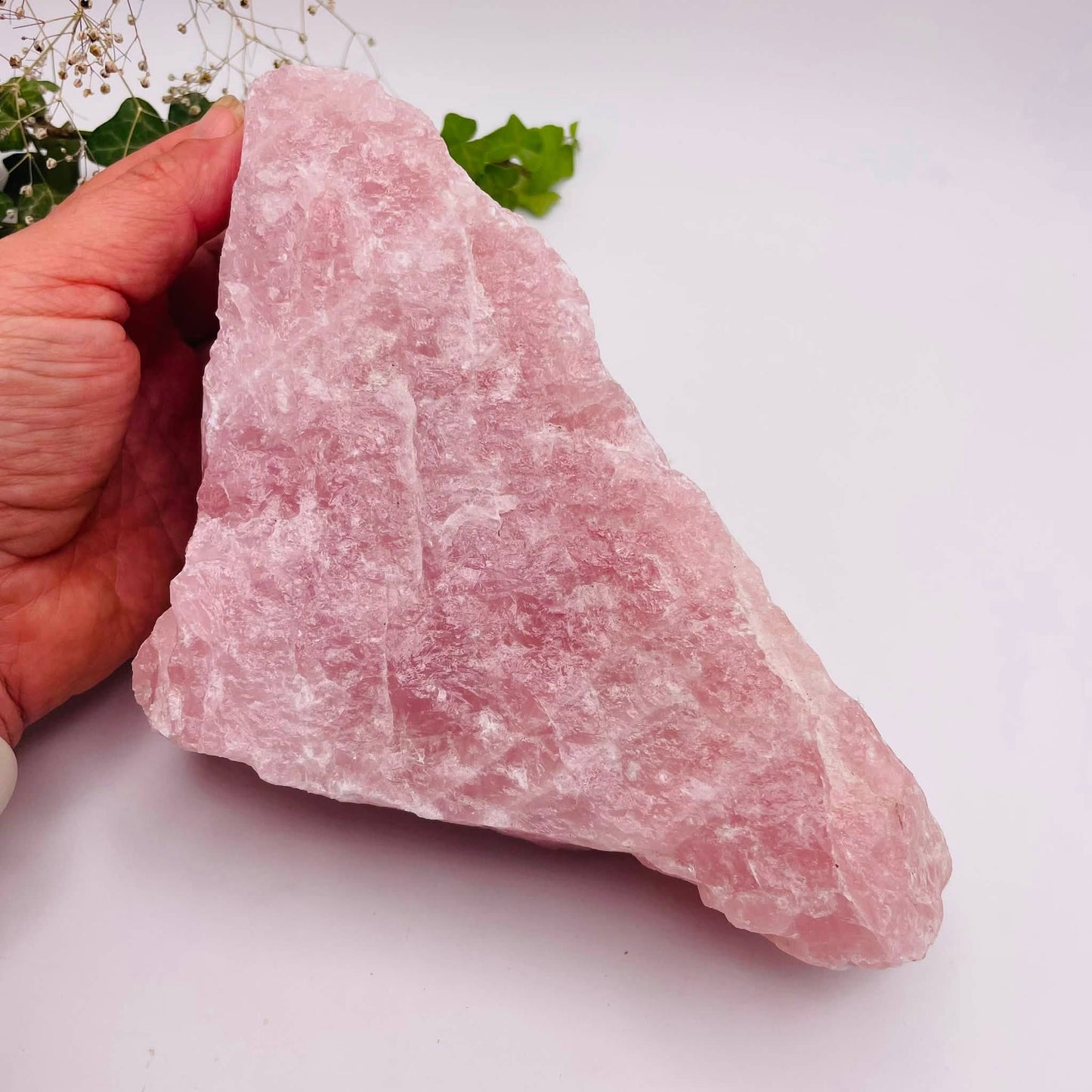 Nahaufnahme eines Rosenquarz-Rohsteins mit zartrosa Farbgebung und natürlicher, unbearbeiteter Kristallstruktur
