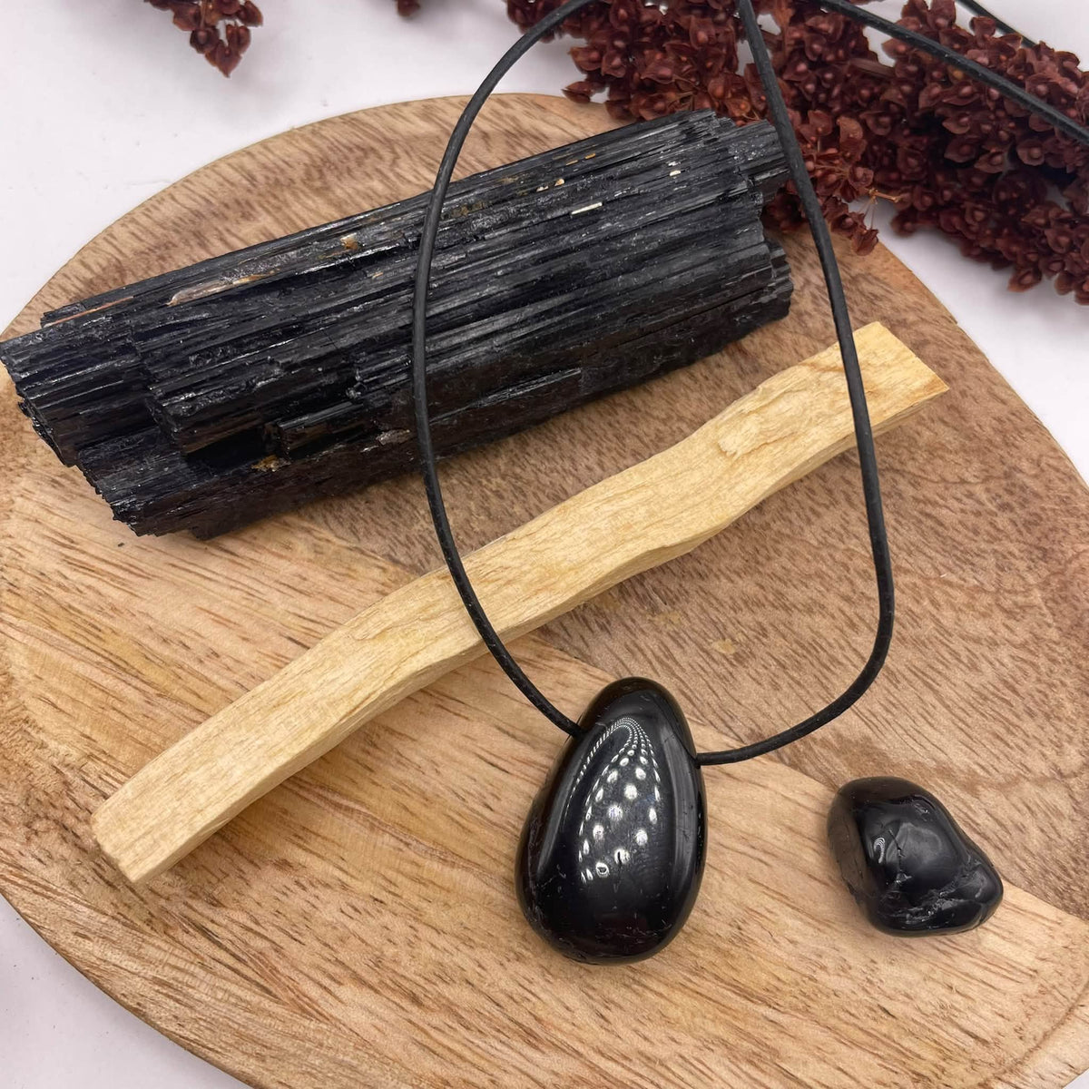 Schutz & Balance Set in der Draufsicht mit Turmalin-Anhänger, Lederband, Trommelstein, Rohkristall und Palo Santo – handverlesen von WUNDERSTEIN
